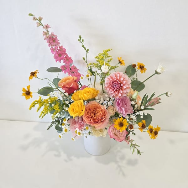 Mixed bouquet in a white vase with pink, yellow, and peach flowers