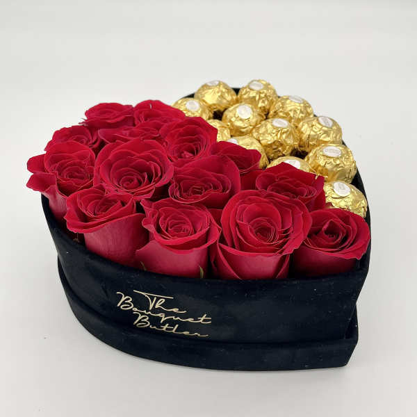 Red roses and gold-wrapped chocolates in a black heart-shaped box
