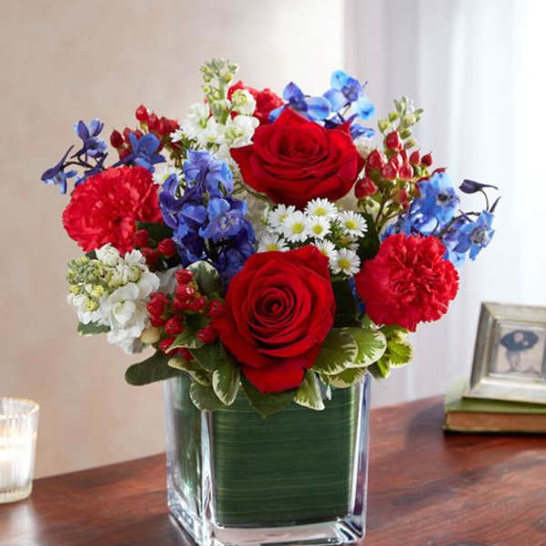Red, white, and blue mixed flower arrangement in a square glass vase