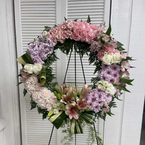 Large pink and white floral wreath on a black stand