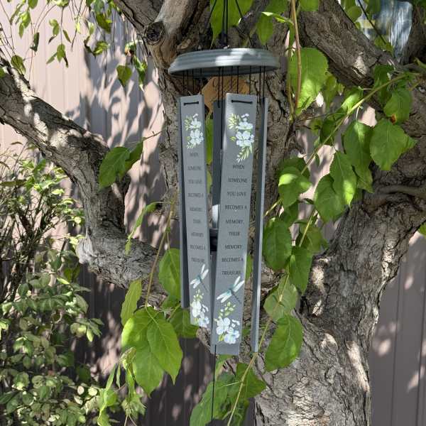 Gray memorial wind chime hanging from a tree with floral accents