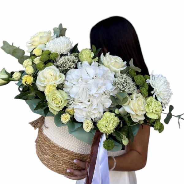 Stylish basket with flowers, in green and fresh shades, for a fashionable girl.