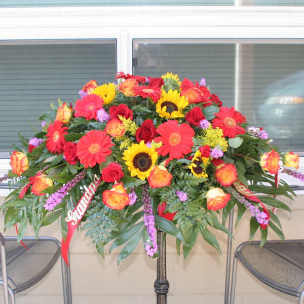 Large mixed flower arrangement on a stand with red, yellow, and orange blooms