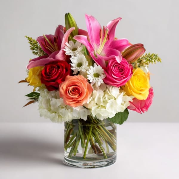 Mixed bouquet of lilies, roses, and white daisies in a glass vase