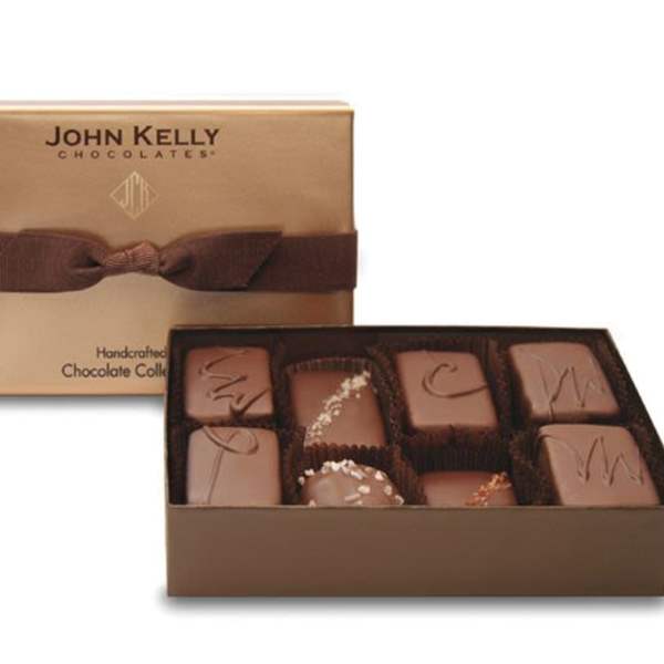 Gold gift box of assorted gourmet chocolates with the lid tied in a wide brown ribbon.