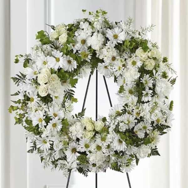 White floral wreath on a black easel stand
