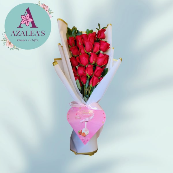 Bouquet of red roses wrapped in white paper with a pink heart-shaped chocolate box