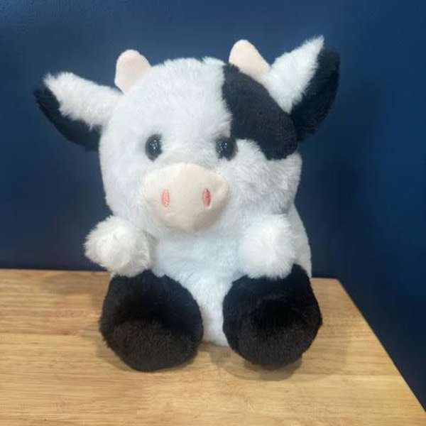 Plush black-and-white cow sitting on a wooden surface