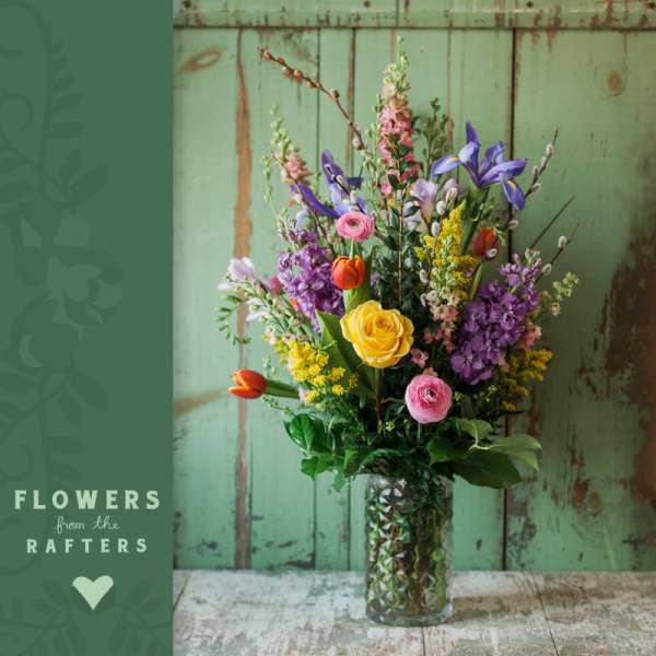Mixed bouquet in a glass vase with yellow, pink, purple, and orange flowers