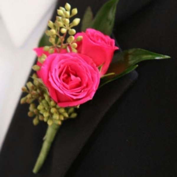 Pink rose boutonniere with small green buds on a black jacket