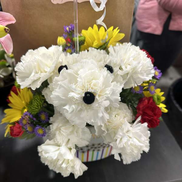 White carnations with colorful daisies in a striped container