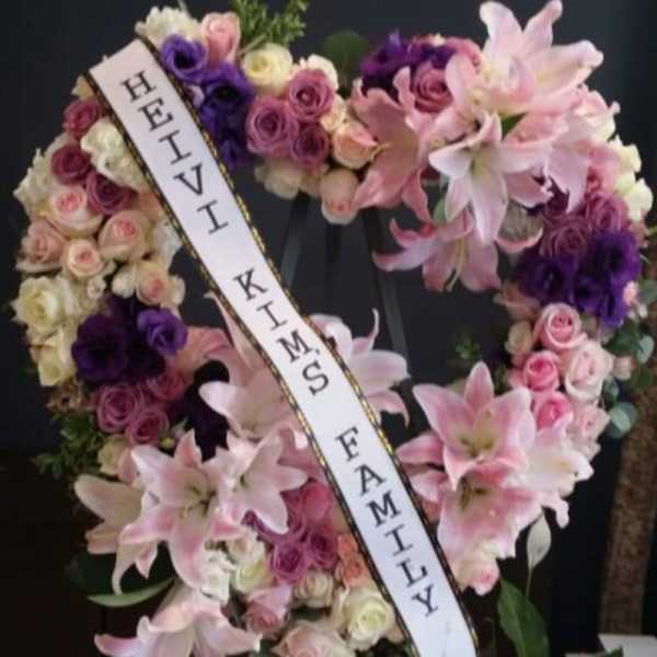 Heart-shaped floral wreath with pink lilies and roses on an easel