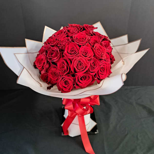 Bouquet of red roses wrapped in white paper with a red ribbon