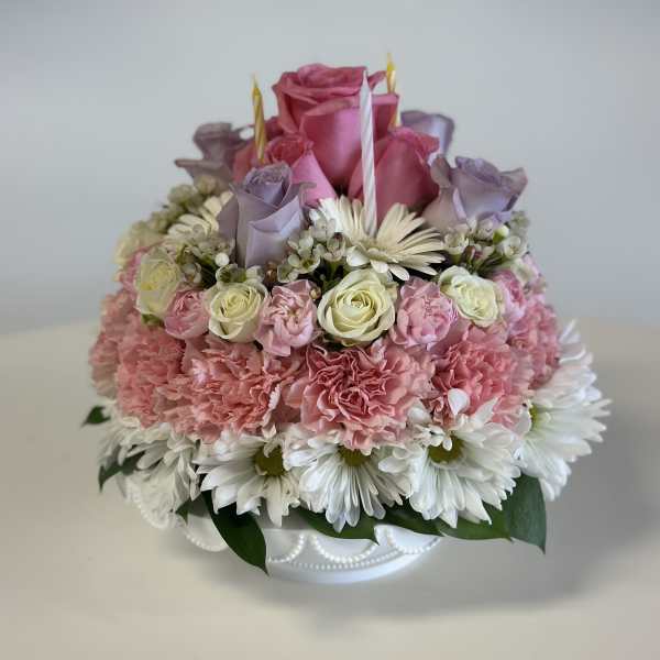 Tiered floral cake with pink roses, carnations, and white daisies