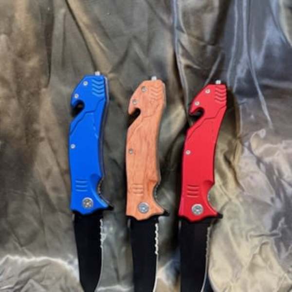 Three folding knives with blue, wood-tone, and red handles on fabric