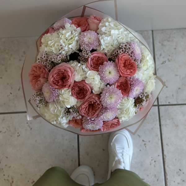 Round bouquet of pink and white flowers wrapped in clear paper