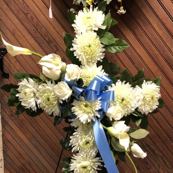 White floral cross with blue ribbon on an easel