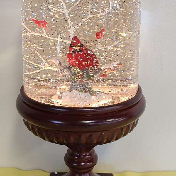 Snow globe with a red cardinal on a wooden pedestal