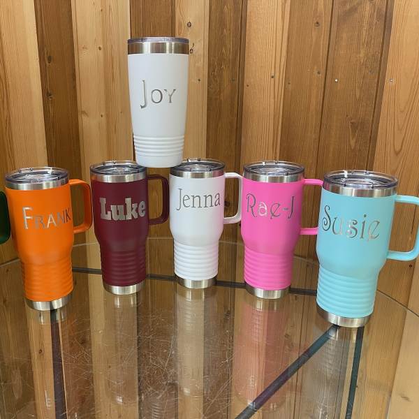 Six personalized insulated tumblers in assorted colors on a glass table