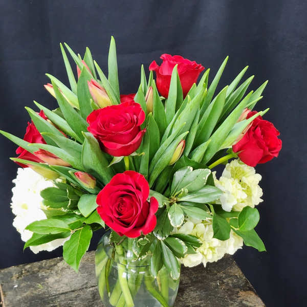 Red roses and white flowers arranged in a glass vase