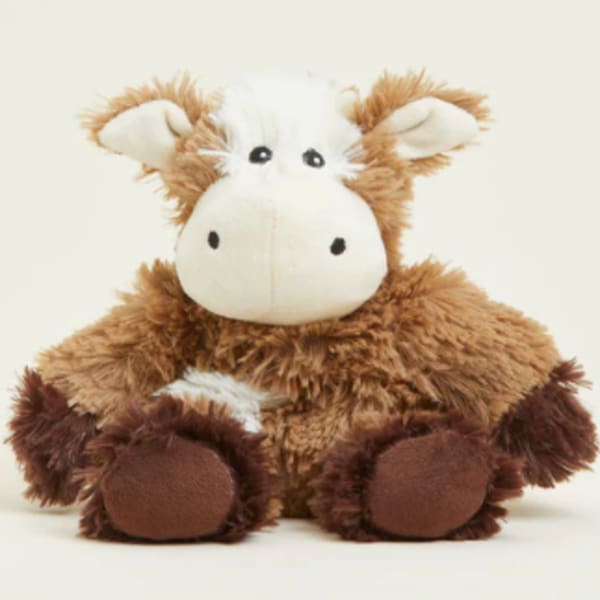 Brown and white plush cow toy sitting against a plain background