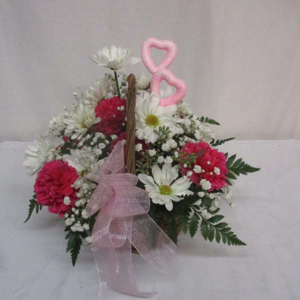 Basket arrangement of white daisies and pink carnations with a pink ribbon bow