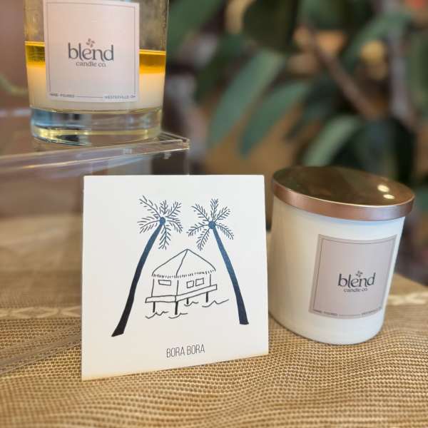 Two candles and a Bora Bora card on a woven surface