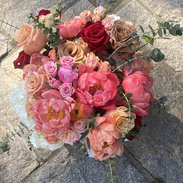 Round bouquet of pink, peach, and red flowers with eucalyptus