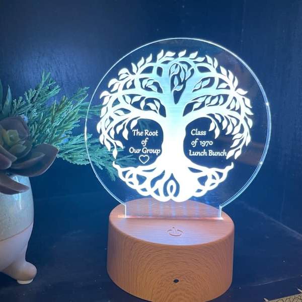 Succulent arrangement in a small ceramic pot beside an engraved LED acrylic plaque