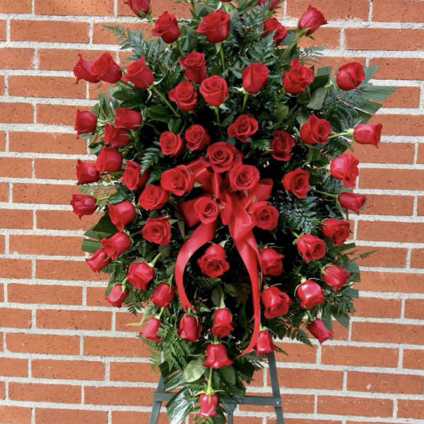 Standing spray of red roses with a red ribbon on a black easel