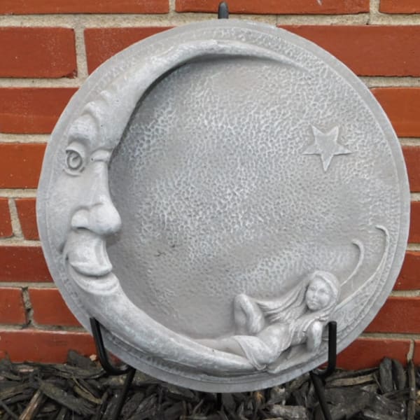 Round gray moon plaque with a face and reclining figure
