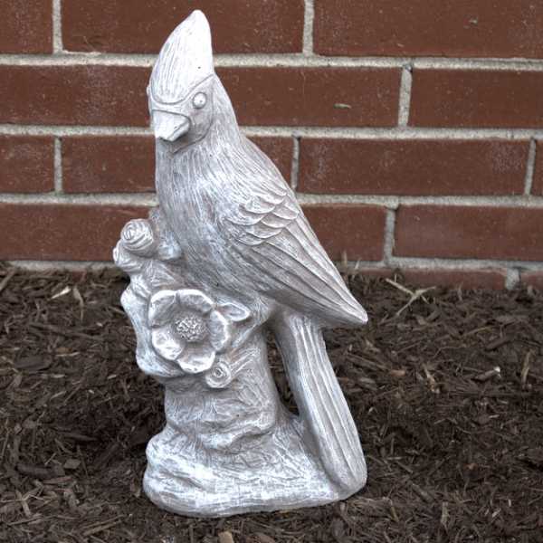 White bird statue holding a flower against a brick wall