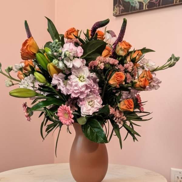 Mixed bouquet of orange and pink flowers in a matte vase