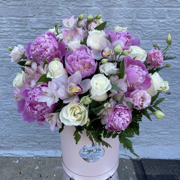 Pink and white mixed flower arrangement in a round box