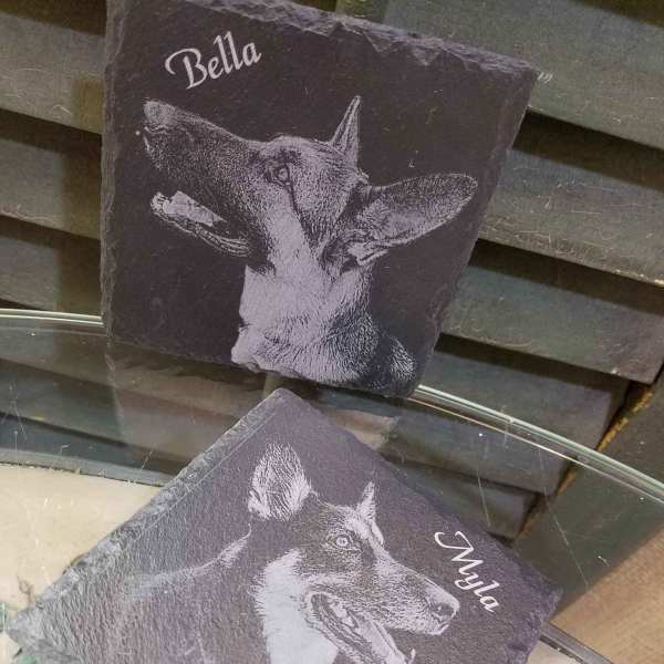 Two personalized slate plaques with dog portraits and names.