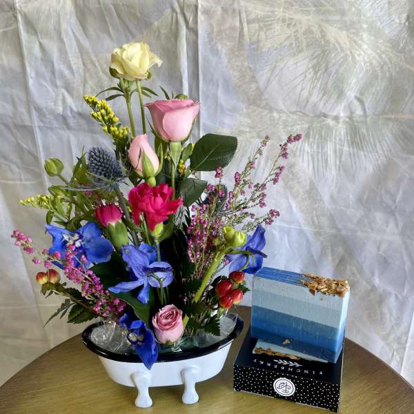 Mixed bouquet in a white vase with pink, blue, and yellow flowers