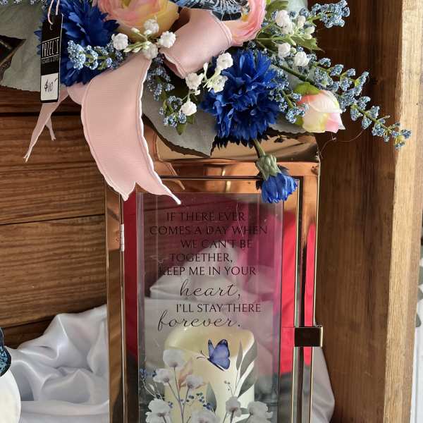 Pink and blue floral arrangement on a rose-gold lantern with a butterfly accent