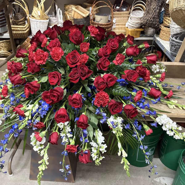 Large red rose arrangement with blue and white flowers in a low container