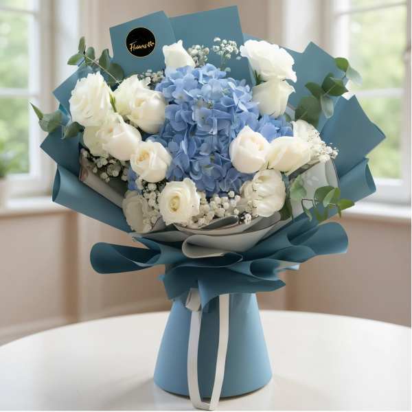 Blue and white bouquet of roses and hydrangeas wrapped in teal paper