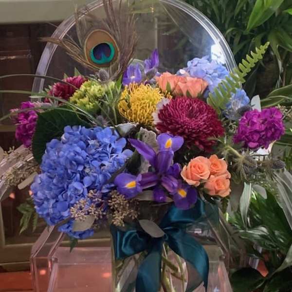 Colorful mixed bouquet in a clear glass vase with a teal ribbon