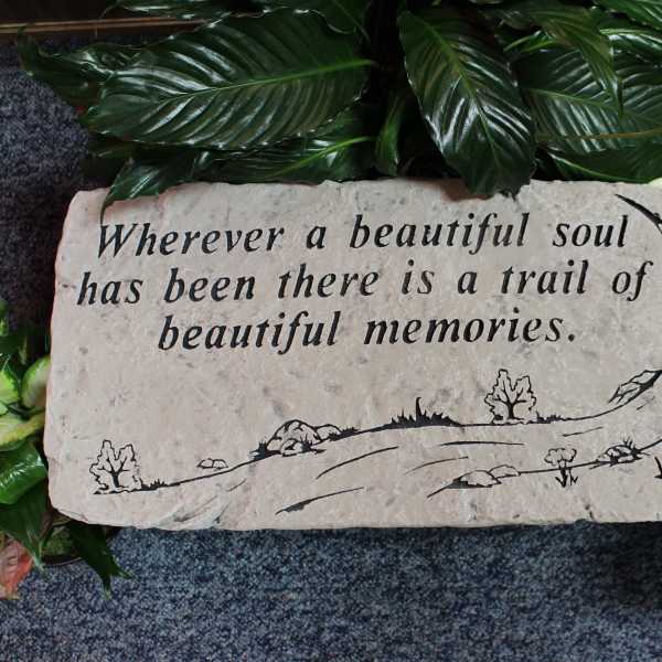 Memorial stone with engraved quote surrounded by green leaves