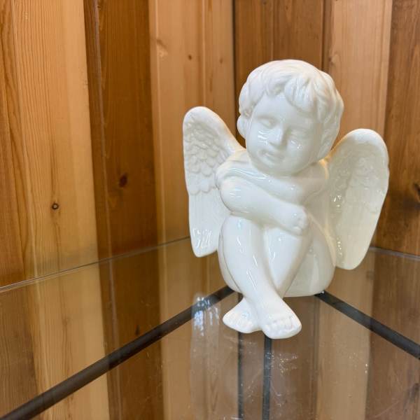 White ceramic angel figurine sitting with wings spread