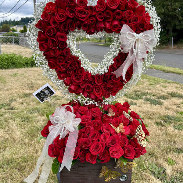 Heart-shaped rose arrangement with white baby's breath and ribbon bows