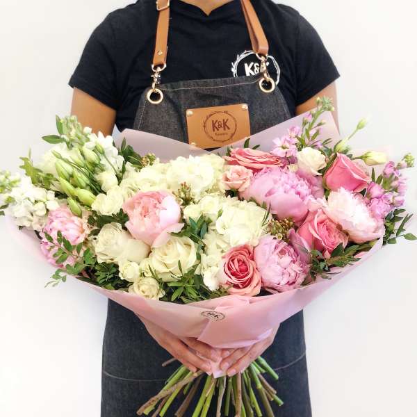 Large bouquet of pink and white flowers wrapped in pale pink paper