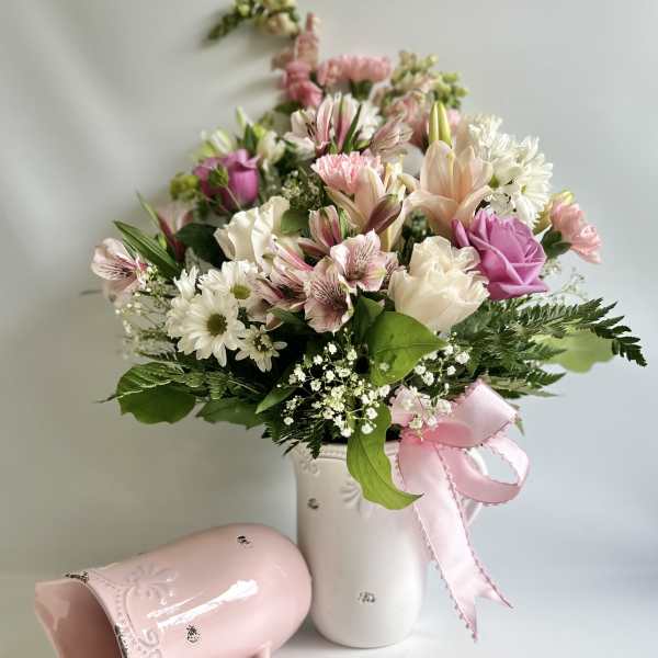 Pink and white mixed bouquet in a white vase with a pink ribbon