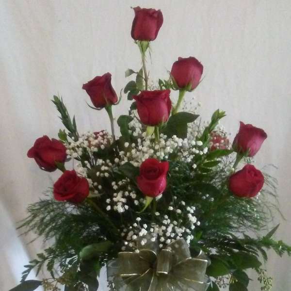 Red roses arranged in a clear glass vase with baby's breath