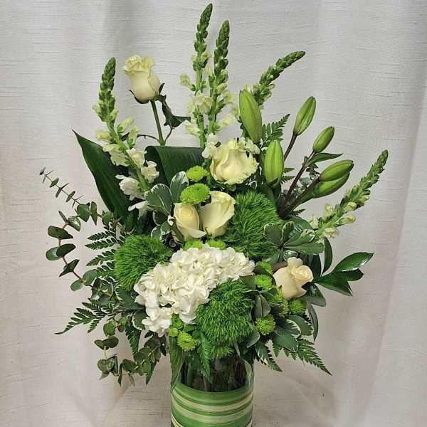 White roses and hydrangea in a green striped vase with mixed greenery