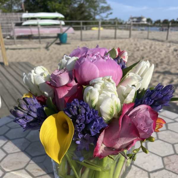 Mixed bouquet with pink roses, white tulips, purple hyacinths, and a yellow calla lily in a glass vase
