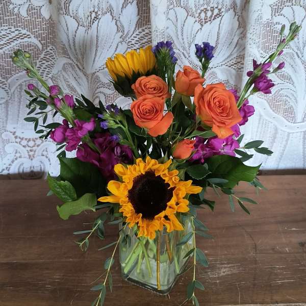Mixed bouquet with orange roses and sunflowers in a glass vase