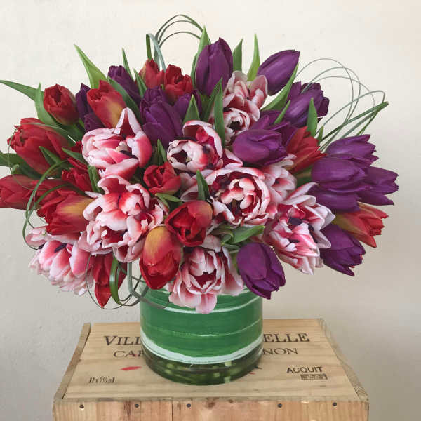 Bouquet of red, pink, and purple tulips in a green glass vase